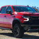 red 2023 chevy silverado zr2 parked on a dirt road, viewed from the front right-hand corner of the vehicle